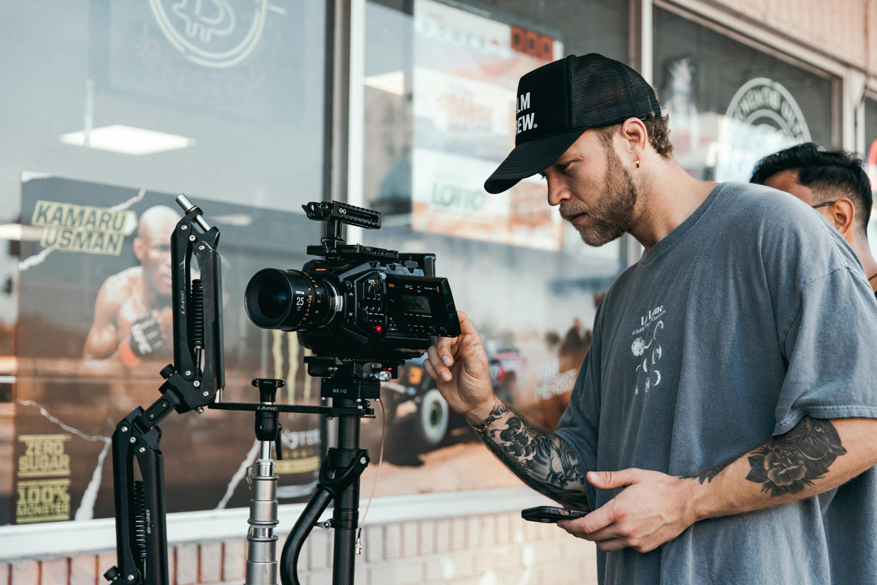 Person operating a camera on a tripod with a blurred background